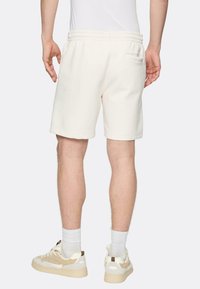 Kermansävyiset puuvillahousut, joissa joustava vyötärönauha ja takatasku. Housuissa on rento istuvuus ja tikattu helmareuna.