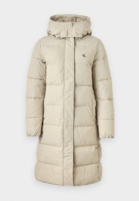 Beige padded coat with hood, featuring a front zipper and snap closure, quilted design, logo on chest, and side pockets.