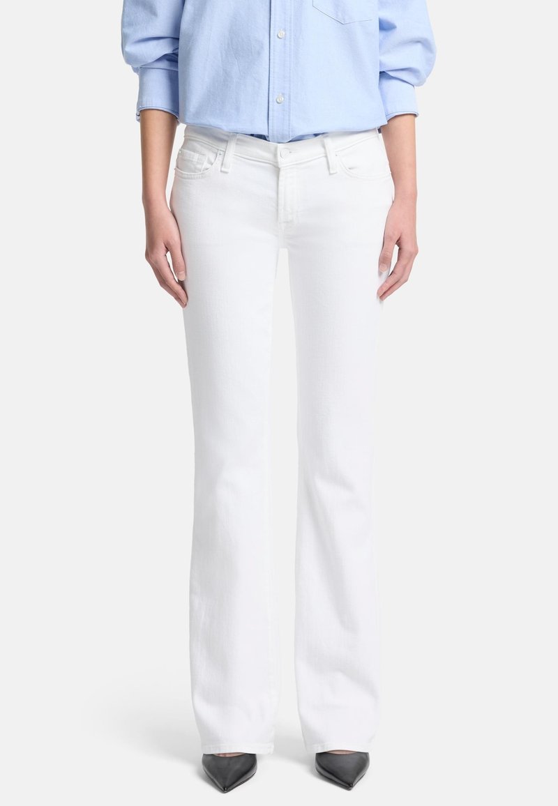 Jeans bianchi a gamba svasata in denim, con vita media, cinque tasche e finitura pulita, abbinati a una camicia azzurra a bottoni.