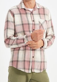 Rood-wit geruit flanellen overhemd met een borstzak, knoopsluiting aan de voorkant, lange mouwen en zwarte accenten in het patroon.