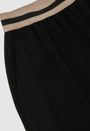 Schwarze Hose mit elastischem Bund und einem hellbraunen sowie dunkel gestreiften Detail. Weiche Textur mit Seitennähten und ohne sichtbare Taschen.