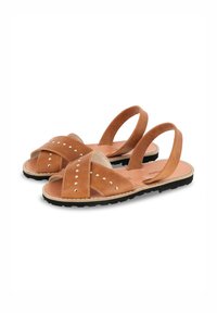 Sandales en cuir brun avec un design à lanières croisées, ornées de clous, et deux sangles arrière. Présentent une semelle intérieure texturée et une semelle en caoutchouc noire.