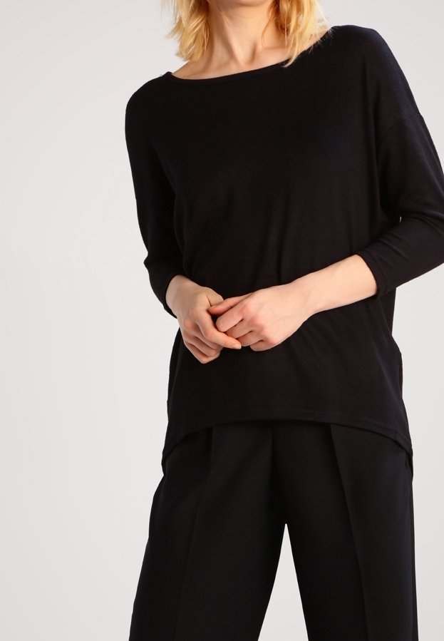 Schwarzer, locker sitzender Pullover mit weitem Ausschnitt und 3/4-Ärmeln, kombiniert mit schwarzen, maßgeschneiderten Hosen. Glatte Textur, minimalistisches Design.