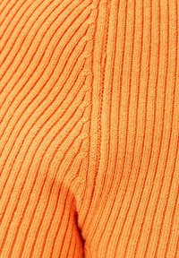 Orange ribbat stickad tyg med vertikala linjer och en texturerad yta, med en slät finish längs kanterna.