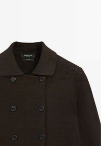 Braune Baumwollstrickjacke mit strukturiertem Muster, ausgestattet mit einem Kragen, doppelreihiger Knopfleiste und sechs schwarzen Knöpfen auf der Vorderseite.