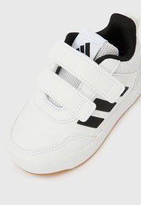 Biela športová obuv s čiernymi akcentmi, s vrchnou časťou zo syntetickej kože, detailmi z sieťoviny a dvoma suchými zipsami. Gumená podrážka.