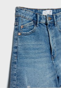 Jeans in denim blu con vita alta, dal tessuto liscio, con cuciture a contrasto, due tasche laterali e dettagli strappati vicino all'orlo.