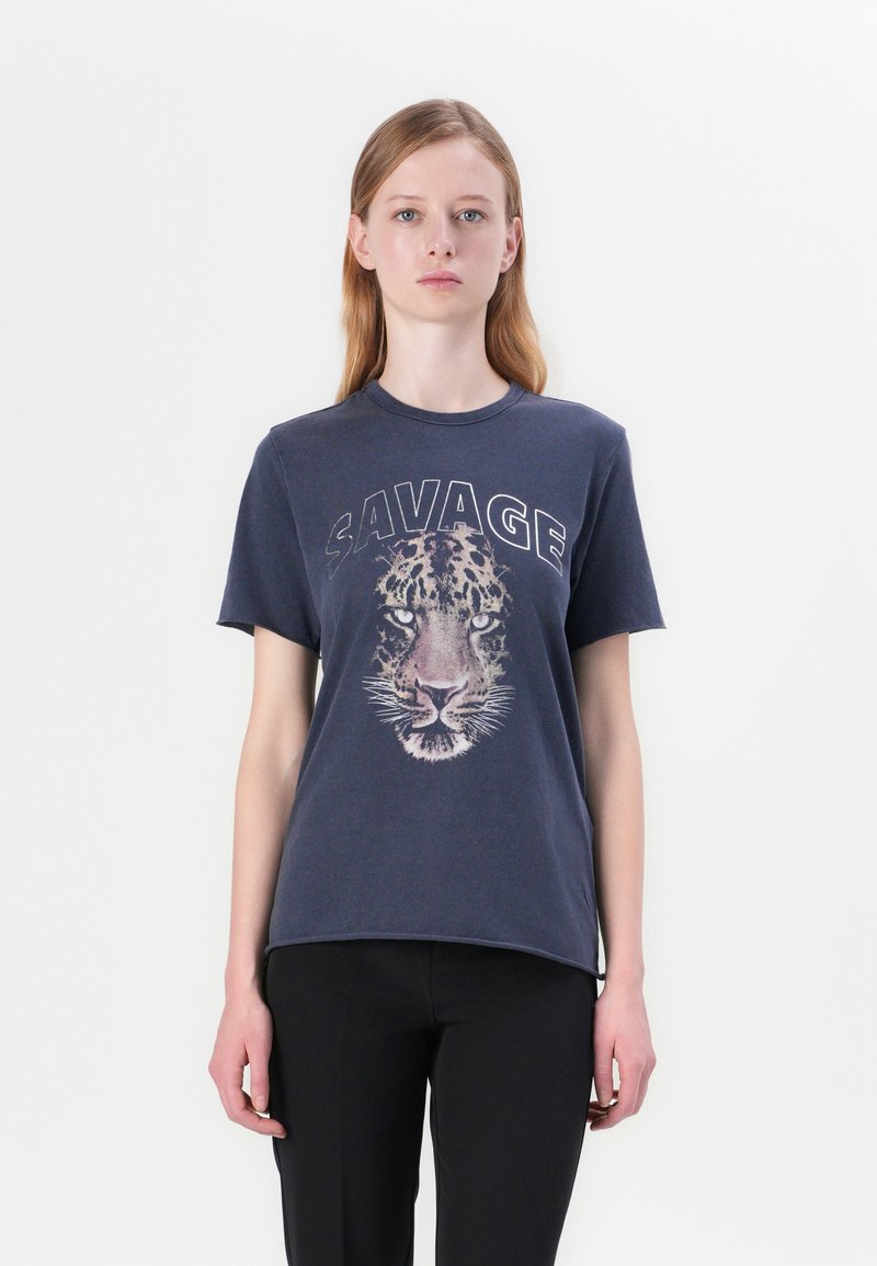 T-shirt in cotone blu navy con una grafica della faccia di una tigre e la parola "SAVAGE" in lettere maiuscole sopra di essa. Maniche corte e scollo rotondo.
