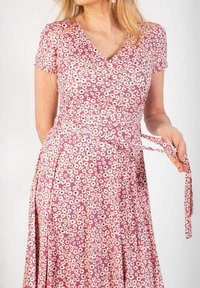 Kukkakuvioinen kietaisumekko purppurassa sävyssä, jossa on lyhyet hihat. Mekossa on V-mallinen kaula-aukko, pieniä valkoisia ja vaaleanpunaisia kukkia sekä vyötärölle solmittava nauha. Kangas on sileä.