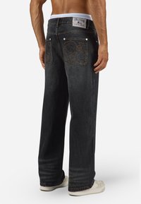 Zwarte baggy spijkerbroeken van denim met een lichte wassing, voorzien van decoratieve achterzakken en een gebrandmerkte tailleband.