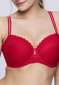 Reggiseno in pizzo rosso con coppe imbottite e con ferretto, bordi ondulati e spalline doppie. Caratterizzato da una zip decorativa sul davanti e dettagli testurizzati.