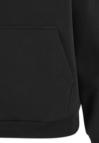 Zbliżenie czarnego materiału z przednią kieszenią kangurką i prążkowanym obszyciem, pokazujące szczegółowe szwy na bluzie lub bluzie z kapturem.