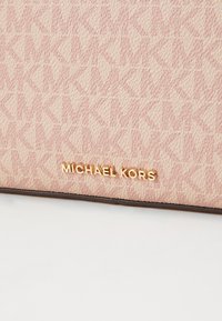 Roze stof handtas met een patroon en een subtiel logo-ontwerp. Gouden "MICHAEL KORS" logo-accent aan de onderkant. Gladde textuur met een gestructureerde vorm.