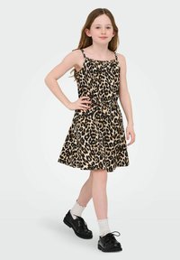 Leoparda raksta kleita, izgatavota no mīksta auduma, ar regulējamiem plecu siksnām, saburzītu jostas vietu un platu svārku. Apvienota ar melniem apaviem un baltiem zeķēm.