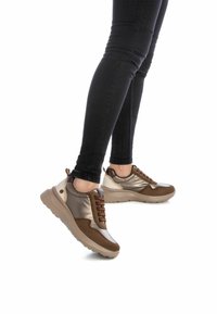 Zapatillas marrones y metálicas con materiales mixtos, que presentan una parte superior suave, acentos texturizados y una suela gruesa beige.