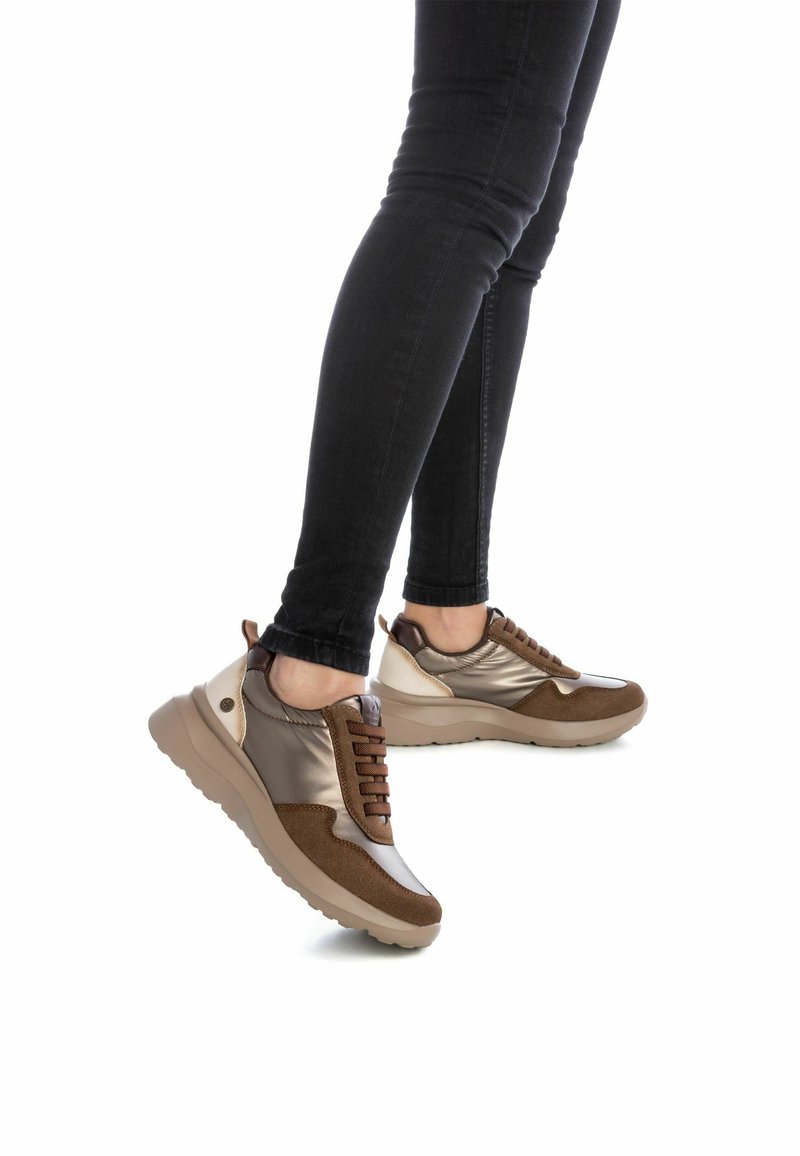 Zapatillas marrones y metálicas con materiales mixtos, que presentan una parte superior suave, acentos texturizados y una suela gruesa beige.