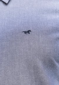 Polo-Shirt aus strukturiertem marineblauen Stoff mit einem dezenten Glanz. Mit kleinem schwarzem Logo eines galoppierenden Pferdes auf der linken Brustseite.
