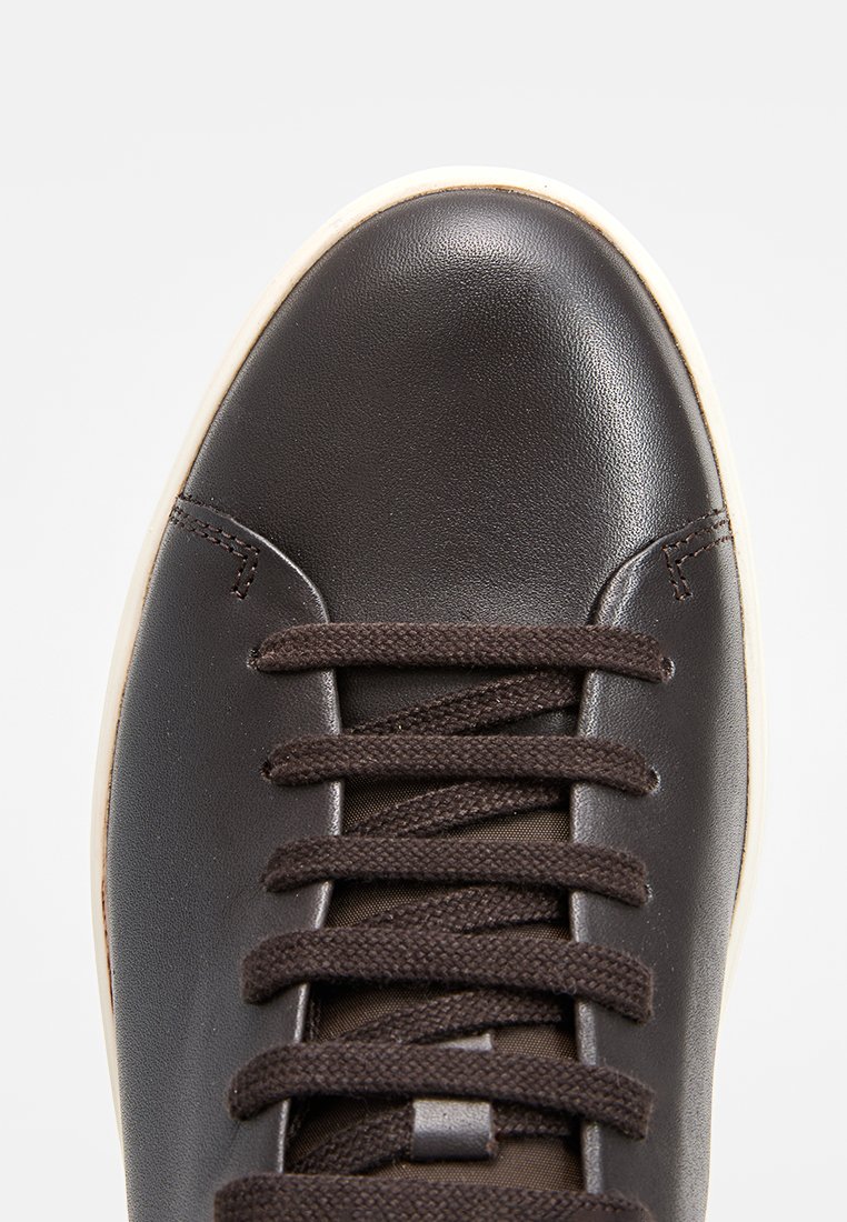 Baskets en cuir marron avec bout rond, présentant des lacets marron, une semelle contrastante blanche cassée, et une texture lisse avec des détails de couture minimes.