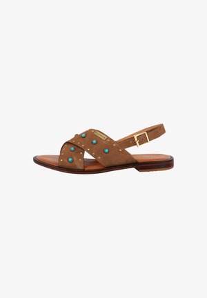 Sandale en suède marron avec des brides croisées, des accents bleus et des clous dorés. Comprend une fermeture à boucle et une semelle plate pour le confort.