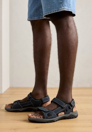 Dunkelblaue Sandalen mit Klettverschlüssen, offenem Zehendesign und strukturierter Sohle. Verfügt über abgesteppten Akzente und atmungsaktive Seitenpanels.