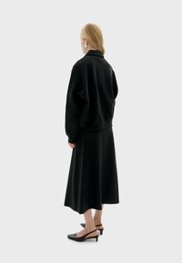 Sort oversized sweatshirt parret med en matchende sort midi-nederdel, der har en glat stof og en afslappet pasform. Sorte slingback hæle fuldender looket.