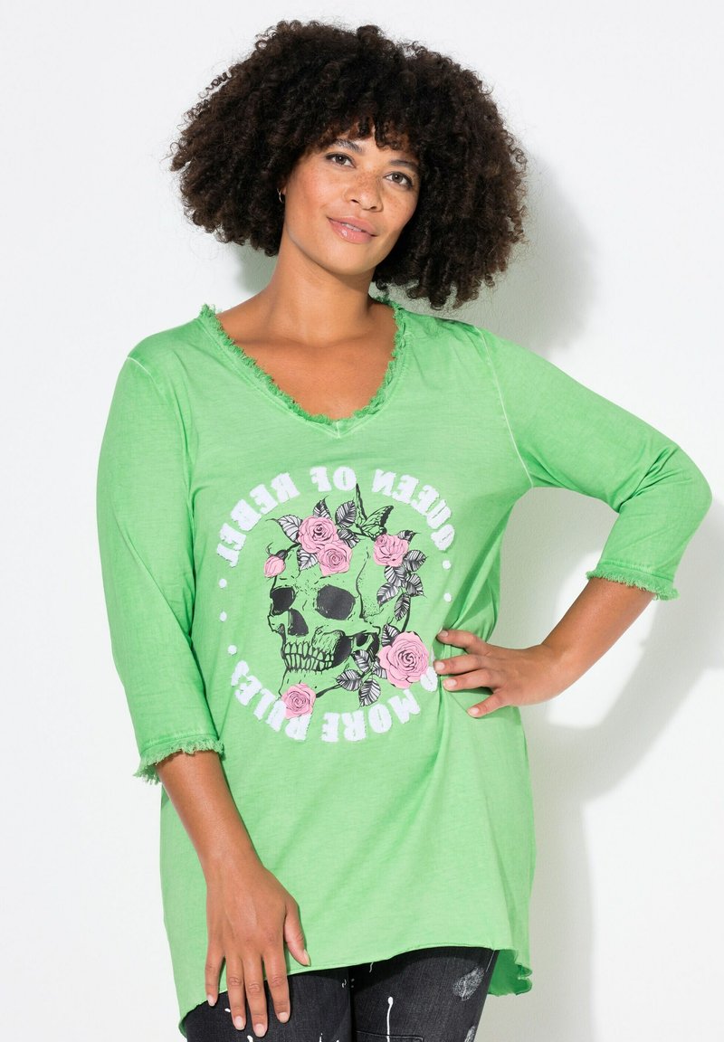 Chemise tunique en coton vert avec un col en V usé, des manches 3/4, présentant un graphique de crâne et de rose, et une coupe décontractée avec des bords effilochés.