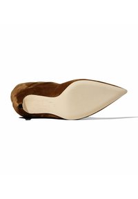 Zapato de tacón stiletto de ante marrón con un diseño de punta afilada y suela de goma color crema que presenta una marca grabada en la plantilla.