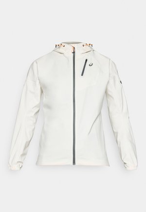 Lichte, witte jas met een rits aan de voorkant, een verstelbare capuchon en elastische manchetten. Voorzien van een grijze ritsborstzak en logo-accent.