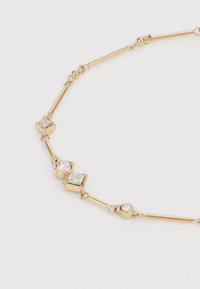 Collier en métal doré ornés de maillons géométriques avec des accents en zircon cubique transparent, alternant entre des formes carrées et rondes.