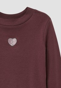 Burgunderfarbendes Langarmshirt mit Rundhalsausschnitt, versehen mit einer pinken, glitzernden Herzstickerei auf der Brust. Glatte Stofftextur.