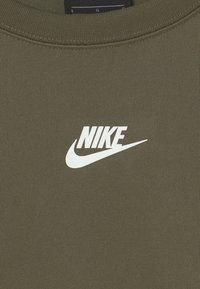 Olivgrön sweatshirt i texturerad väv, med en vit Nike-logotyp i mitten och en swoosh under.