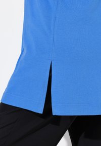 Blaues Baumwoll-T-Shirt mit geradem Schnitt und seitlichen Schlitzen am Saum. Der Stoff hat eine glatte Textur und eine einheitliche Farbe.