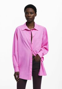 Roze overhemddetails met lange mouwen en een zak. Gemaakt van een gladde stof, heeft een losse pasvorm en een iets open halslijn.