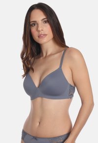 Soutien-gorge gris au design lisse et sans couture. Les détails en dentelle sur les côtés ajoutent de la texture. Bretelles ajustables et forme classique en V.