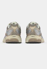 Αθλητικά παπούτσια με μπεζ και γκρι πλέγμα επάνω, υφή σε διάφορα σημεία, μαξιλαρωμένα κολάρα και παχύ μπεζ καουτσούκ σόλα με μαύρες λεπτομέρειες.