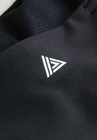 Tissu noir présentant un motif texturé avec un logo triangulaire blanc proéminent et trois bandes horizontales, indiquant les détails de la marque.