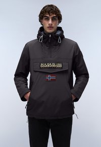 Jachetă anorak în gri închis, cu un mare patch cu logo și detaliu cu steagul Norvegiei pe față, proiectată cu un glugă cu șnur și buzunare cu fermoar.