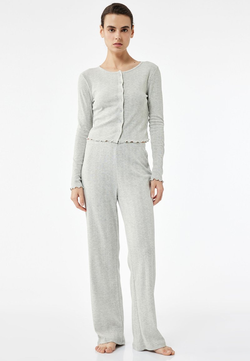 Lichtgrijs geribd pyjama set met een cropped knoopjes-top met een scalloped zoom en bijpassende wijde broek. Zachte, gestructureerde stof.