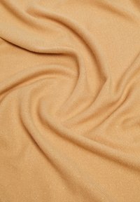 Tessuto arancione chiaro con una consistenza morbida, caratterizzato da una delicata lucentezza e un motivo a coste, drappeggiato in morbide pieghe.