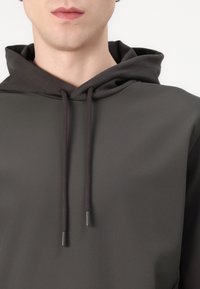 Dark gray hoodie featuring a textured fabric, drawstrings with metal tips, and a relaxed silhouette, highlighting a minimalistic design.