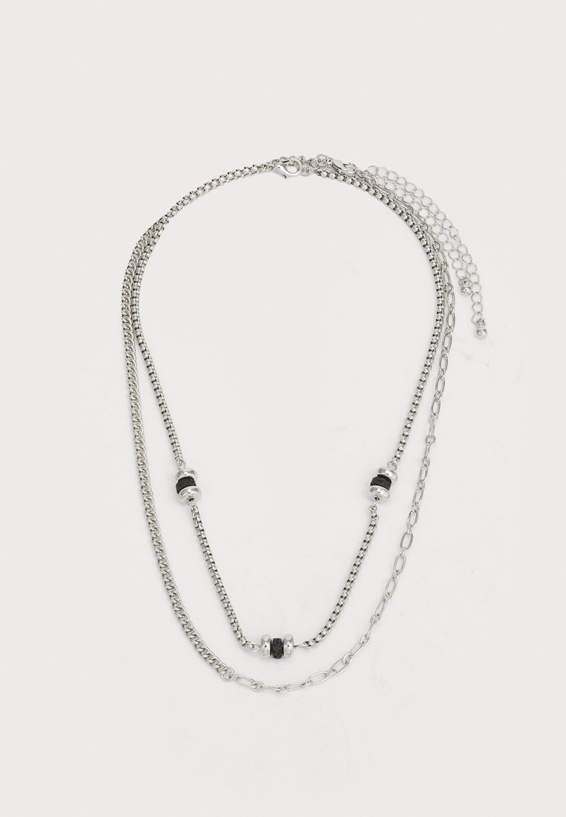Silver multi-layered necklace featuring three strands, interspersed with black and silver beads, with varied chain styles and lengths.