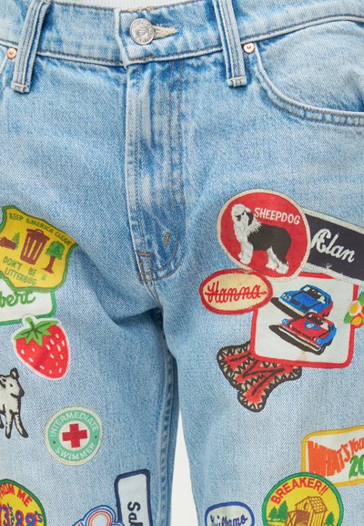 Jeans din denim de culoare albastră deschisă, cu broderii colorate, inclusiv un câine ciobănesc, o căpșună, mașini de curse și mesaje ecologice.