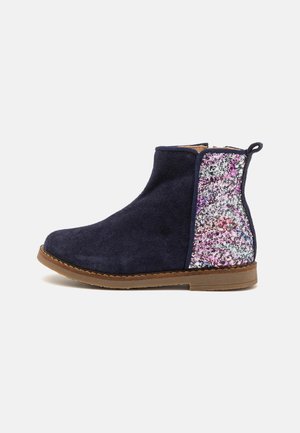 Marineblaues Wildleder-Stiefelette mit einem funkelnden, mehrfarbigen Seitenpaneel, runder Spitze, niedrigem braunen Gummiabsatz und Zugschlaufe für einfaches Anziehen.