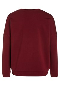 Sudadera burdeos con un diseño sencillo y ajustado, con cuello y bajos de canalé, mangas largas y una textura suave.