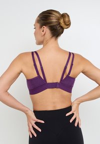 Sportivo viola con dettagli testurizzati, spalline regolabili e chiusura a gancio sul retro. Materiale ad alta elasticità per un buon supporto.