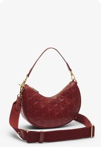 Sac à main en cuir rouge avec une forme courbée, présentant un motif géométrique texturé. Il possède une fermeture éclair dorée et une bandoulière amovible.