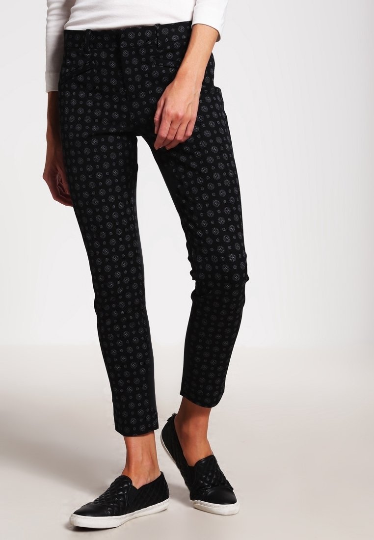 Černé patterned kalhoty s přiléhavým střihem a jemnými květinovými motivy, vyrobené z pružného materiálu, doplněné černými pohodlnými botami na zpevnění.