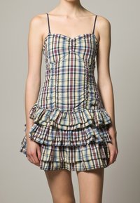 Kárované mini šaty s přiléhavým tělem, volánkovou sukní a tenkými ramínky. Barvy zahrnují žlutou, modrou a burgundskou.