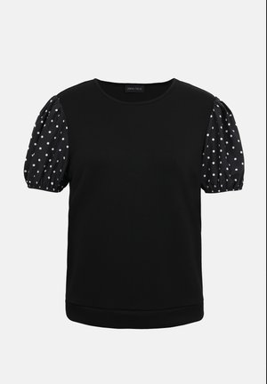 Černý krátký top s kulatým výstřihem a nadýchanými rukávy s černou látkou s bílými puntíky.