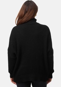 Schwarzer Strickpullover mit hohem Kragen, lockerer Passform, überschnittenen Schultern und Rippstruktur, der ein grobes, texturiertes Design zur Schau stellt.